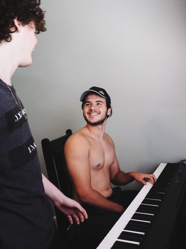 boys sitting at a keyboard while taking piano lessons for their homeschool elective