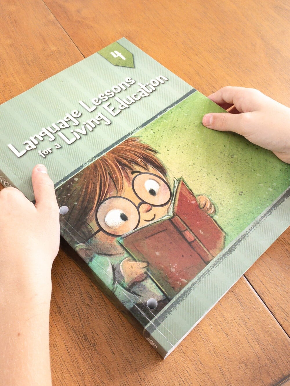 a young boy holding the language lessons for a living education 4th-grade language arts homeschool curriculum