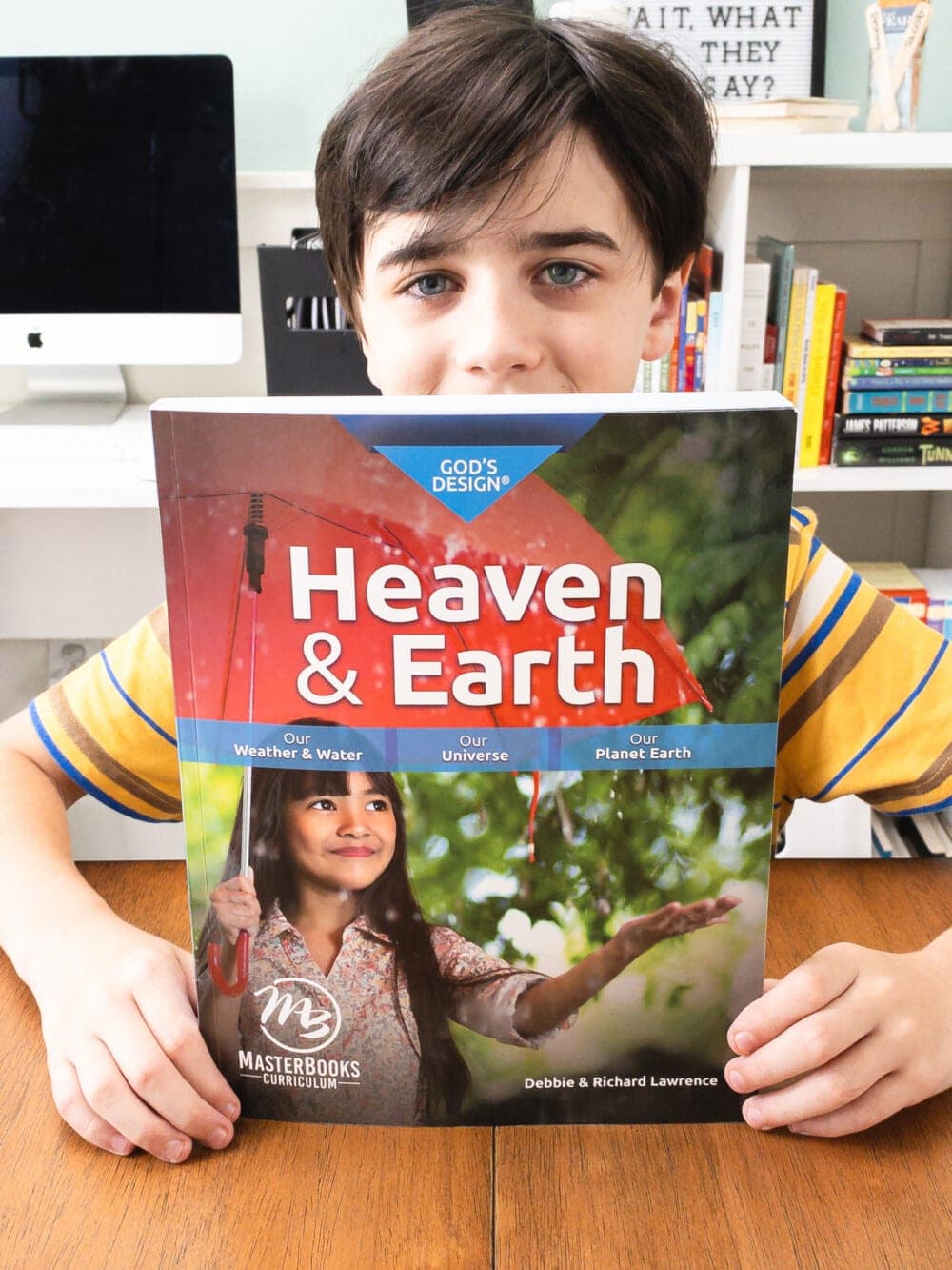 a young boy holding up the masterbooks design for heaven and earth 4th grade homeschool science curriculum