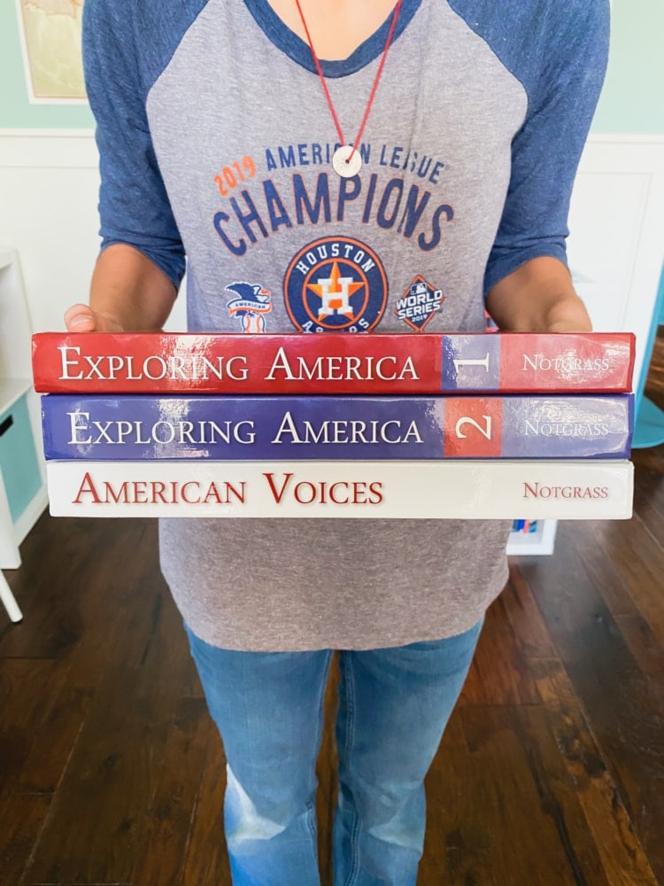 close up of a girl holding a stack of notgrass exploring america books