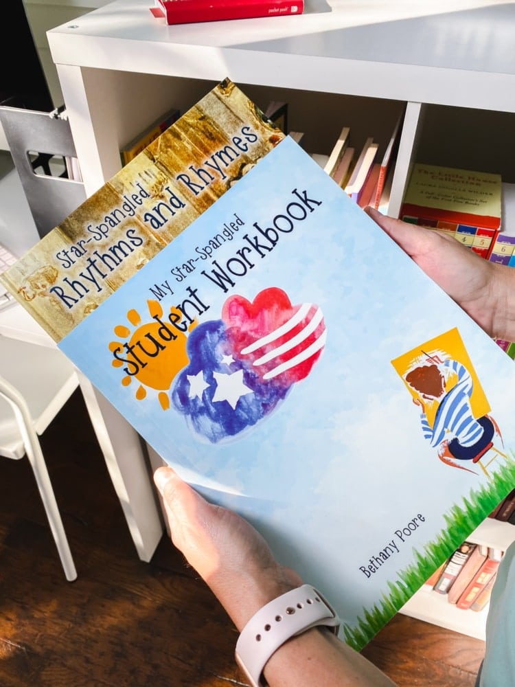 top view of hands holding my star spangled workbook and rhythm and rhymes book from notgrass homeschool history curriculum