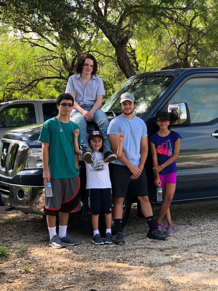 group of children standing around a van in a parking lot