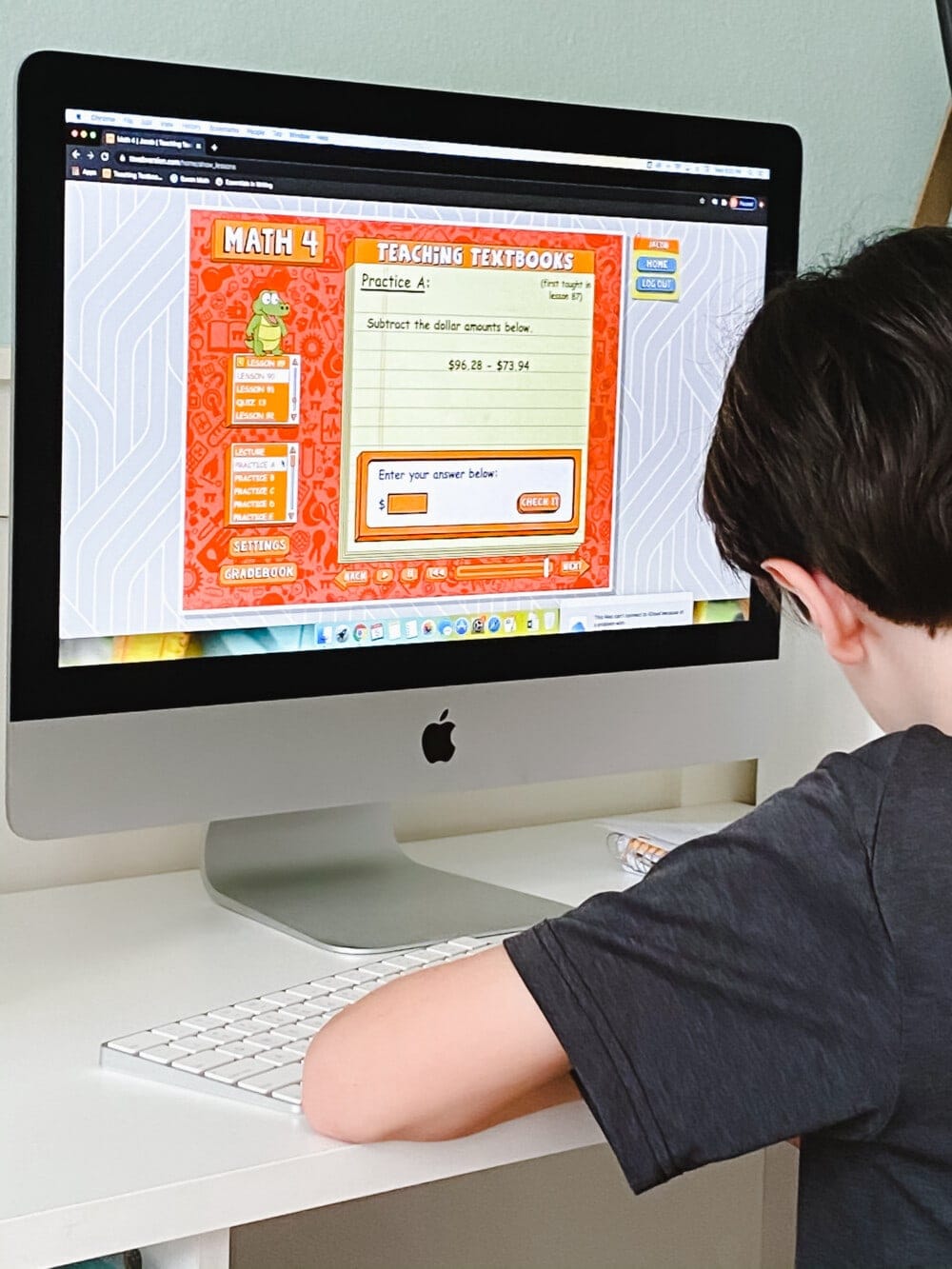 a young boy working at a desktop computer displaying the teaching textbooks math curriculum