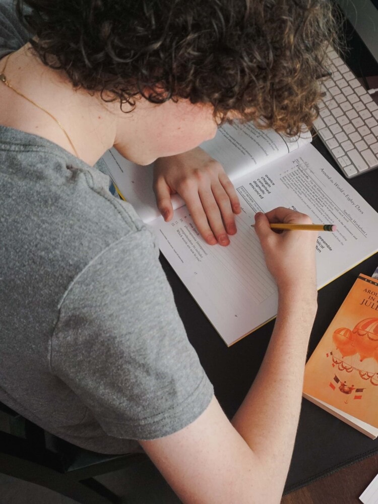 a boy writing down notes for english on an index card