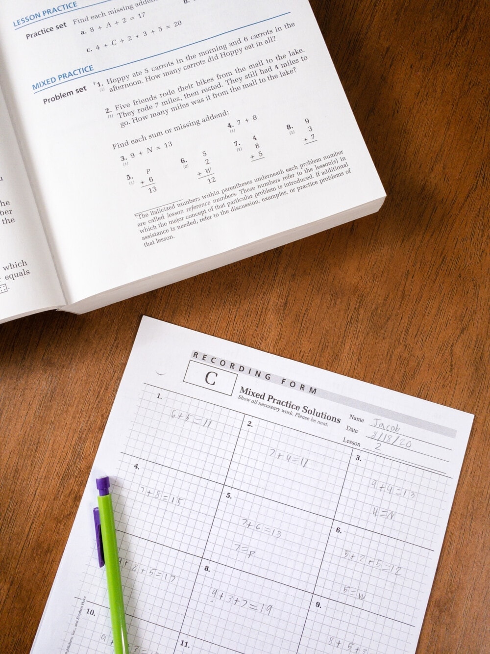 the saxon math 5/4 student workbook with a mixed practice worksheet sitting on a desk