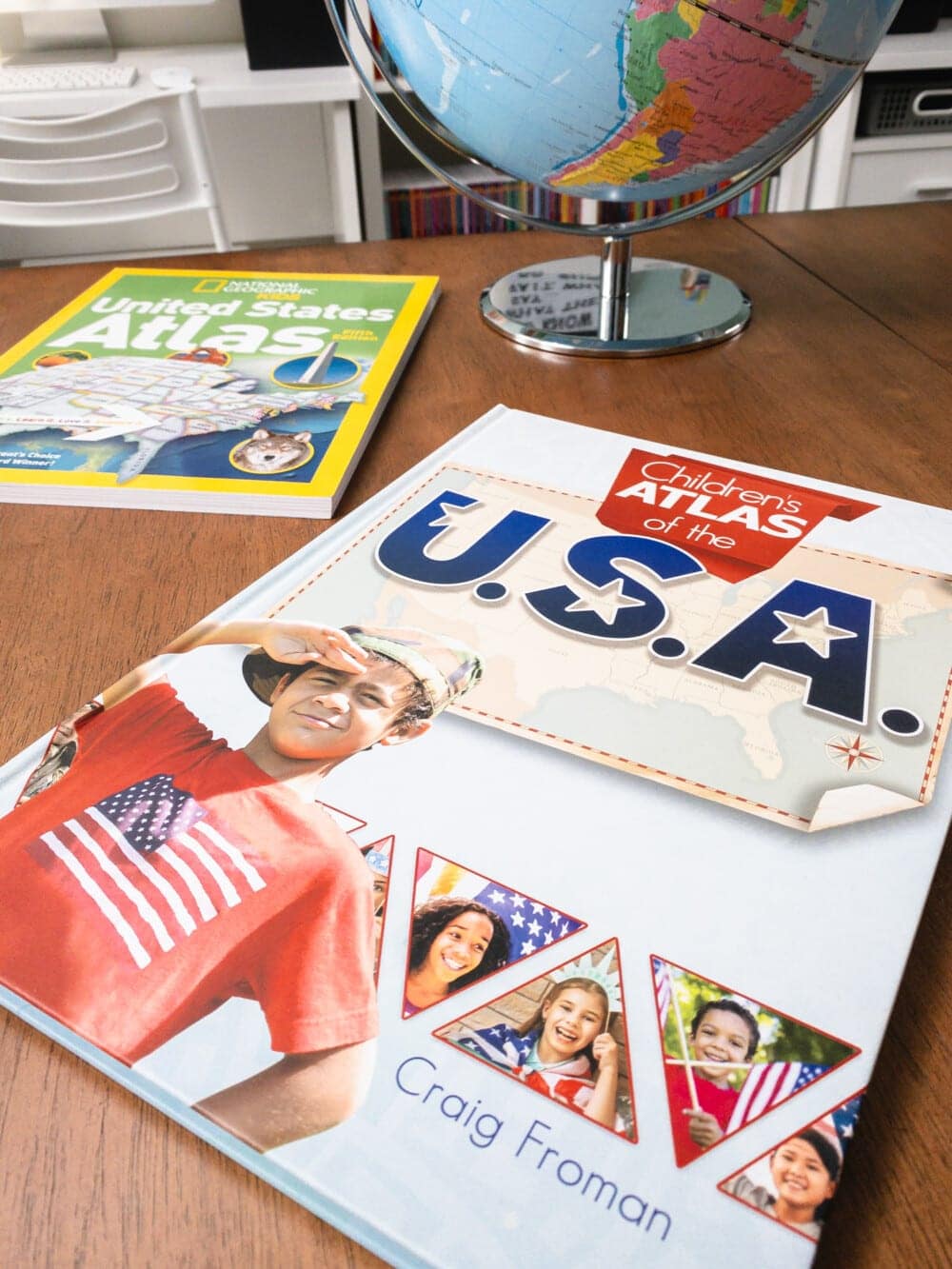 two us atlas books and a globe sitting on a table