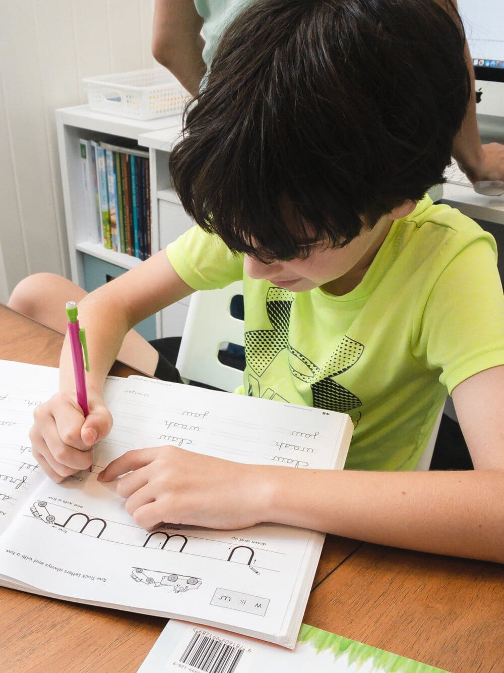 a child practicing handwriting lessons at a table during homeschool